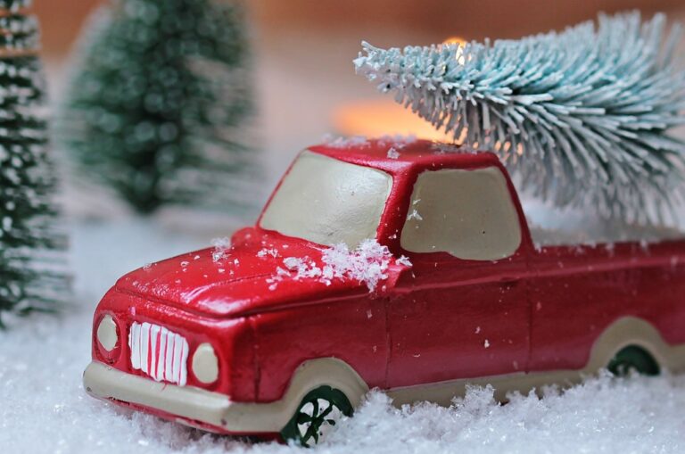 rode miniatuur auto met kerstboom in sneeuw