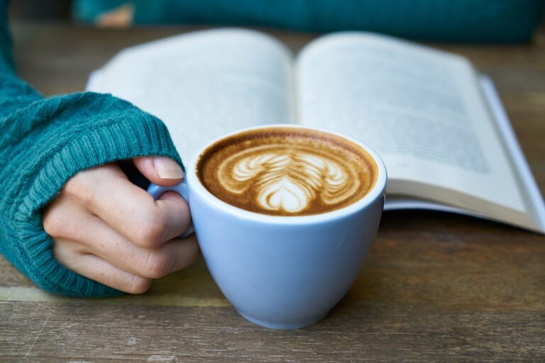 hand met cappuccino en boek